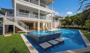 A two-story house with a swimming pool, outdoor seating, and a staircase leading to the upper level. - Thanksgiving availability! Stunning pool home! (Holmes Beach)