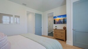 A bedroom with a bed, a dresser, a painting, and a door. - Thanksgiving availability! Stunning pool home! (Holmes Beach)