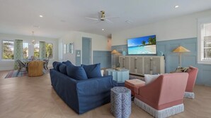 A spacious living area with a sofa, chairs, a TV, and a dining table. - Thanksgiving availability! Stunning pool home! (Holmes Beach)