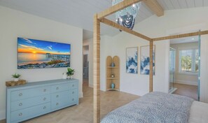 A bedroom with a bed, a dresser, a painting of a sunset, and a view through an open door. - Thanksgiving availability! Stunning pool home! (Holmes Beach)