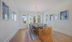 A dining area with a table set for four, surrounded by chairs, with artwork on the walls and a chandelier above. - Thanksgiving availability! Stunning pool home! (Holmes Beach)