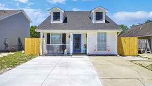 A two-story house with a front porch, a garage, and a fenced yard. - SandSational Staycation Pet Friendly, Fenced Yard, 6min to the Beach (Navarre Beach)