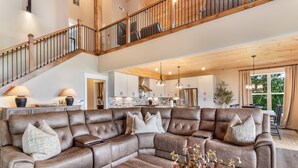 A spacious living area with a large sectional sofa, a wooden coffee table, and a staircase leading to an upper level. - Stunning Views | Sauna | Hot tub | Bar- 2 Kitchens (Ranger)