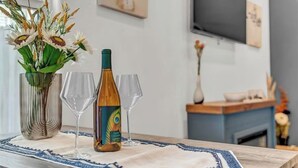 Un coin repas avec une table en bois, un vase rempli de fleurs et une bouteille de vin.