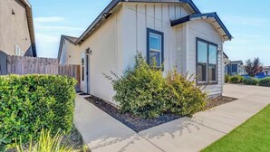 Une maison moderne de plain-pied, dotée d’un porche abrité, d’une pelouse bien entretenue et d’une clôture en bois.