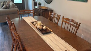 A dining area with a wooden table, chairs, a decorative tray, and a mirror on the wall. - Cottage at Sunnyside/Private/5 Wooded Acres/Garage (Bowling Green)