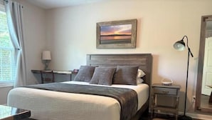 A neatly arranged bedroom with a bed, bedside table, lamp, and a painting on the wall. - Cottage at Sunnyside/Private/5 Wooded Acres/Garage (Bowling Green)