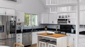 A modern kitchen with white cabinetry, a central island, and a dining area with a round table.