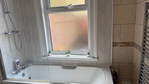 A bathroom with a bathtub, a shower, and a window with frosted glass. - 1 Bed Flat - Sleeps 5 - Parking - Wifi (Leicester)