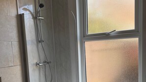 A bathroom with a bathtub, a shower, and a window with frosted glass. - 1 Bed Flat - Sleeps 5 - Parking - Wifi (Leicester)