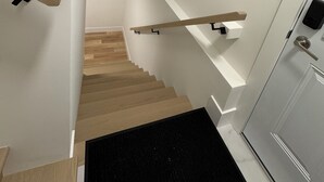 Un escalier moderne avec des marches en bois et un tapis noir au bas.