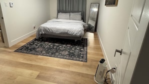 Une chambre à coucher avec un lit, un tapis, un tableau et un radiateur.