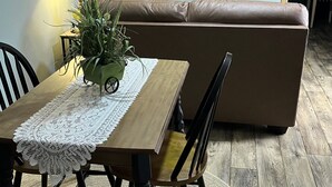Ein Essbereich mit Tisch, Stühlen, einer Lampe, einer Pflanze und einem Sofa.