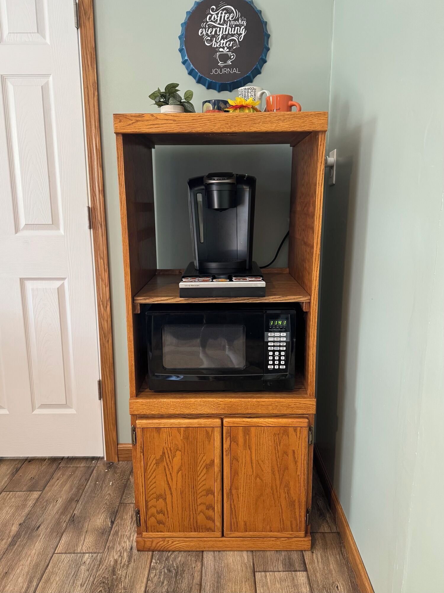Een houten kast met een koffiezetapparaat en magnetron erboven.