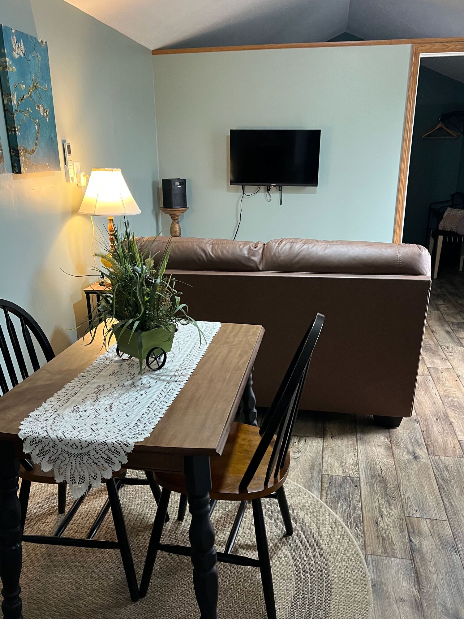 A dining area with a table, chairs, a lamp, a speaker, and a sofa.