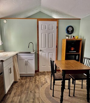 A compact kitchen with a sink, cabinets, and a dining area with a table and chairs.