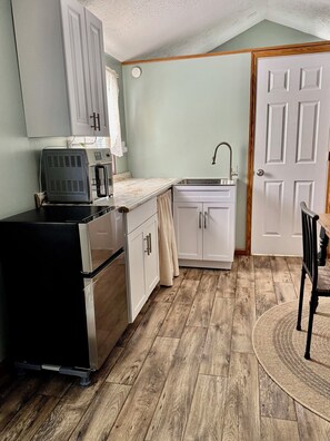 A compact kitchen with a microwave, oven, and sink.