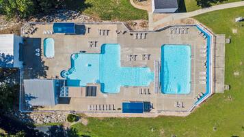 An aerial view of a resort with multiple swimming pools, sun loungers, and a covered area with a pool.