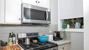 Una cocina moderna con electrodomésticos de acero inoxidable, estufa a gas, microondas y tostadora.