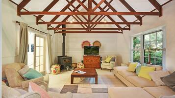 A cozy living room with a wooden ceiling, a sofa set, a coffee table, and a fireplace.