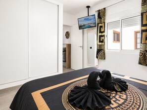 A hotel room with a bed, a TV, and a view of the outside.