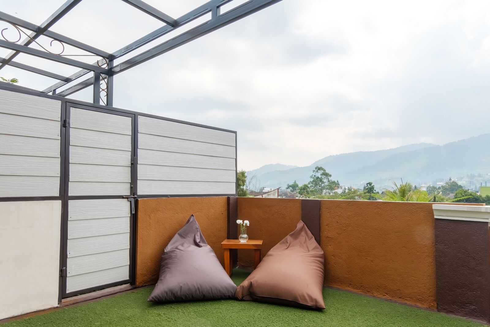Un balcon agrémenté d’un revêtement de sol en gazon synthétique, de deux coussins et d’une petite table sur laquelle est posé un vase de fleurs.