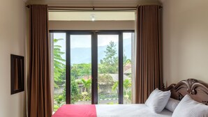 A bedroom with a bed, curtains, and a view of greenery and mountains. - Salma Syariah by TwoSpaces, Bogor (Cisarua)