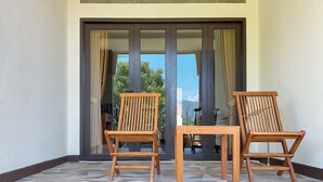 Two wooden chairs facing a sliding glass door with a view of a mountain landscape. - Salma Syariah by TwoSpaces, Bogor (Cisarua)