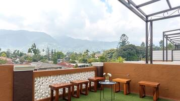 A rooftop terrace with a view of mountains and a cityscape.