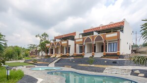 A modern hotel with a pool area, featuring a pool, a covered walkway, and a landscaped garden. - Salma Syariah by TwoSpaces, Bogor (Cisarua)