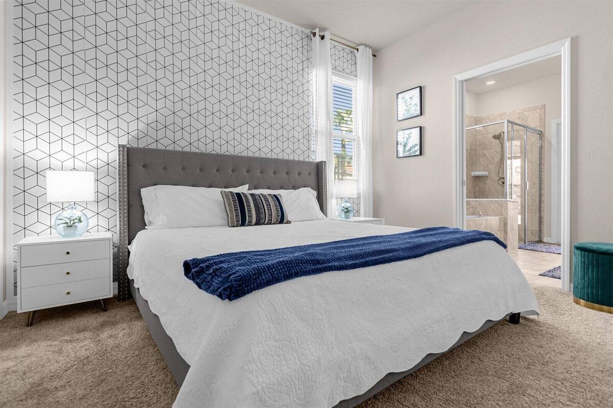 A bedroom with a bed, a nightstand, a lamp, and a window with curtains.