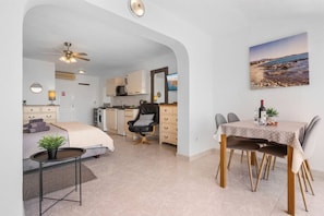 A compact, modern apartment with a kitchenette, a dining area, and a bedroom.