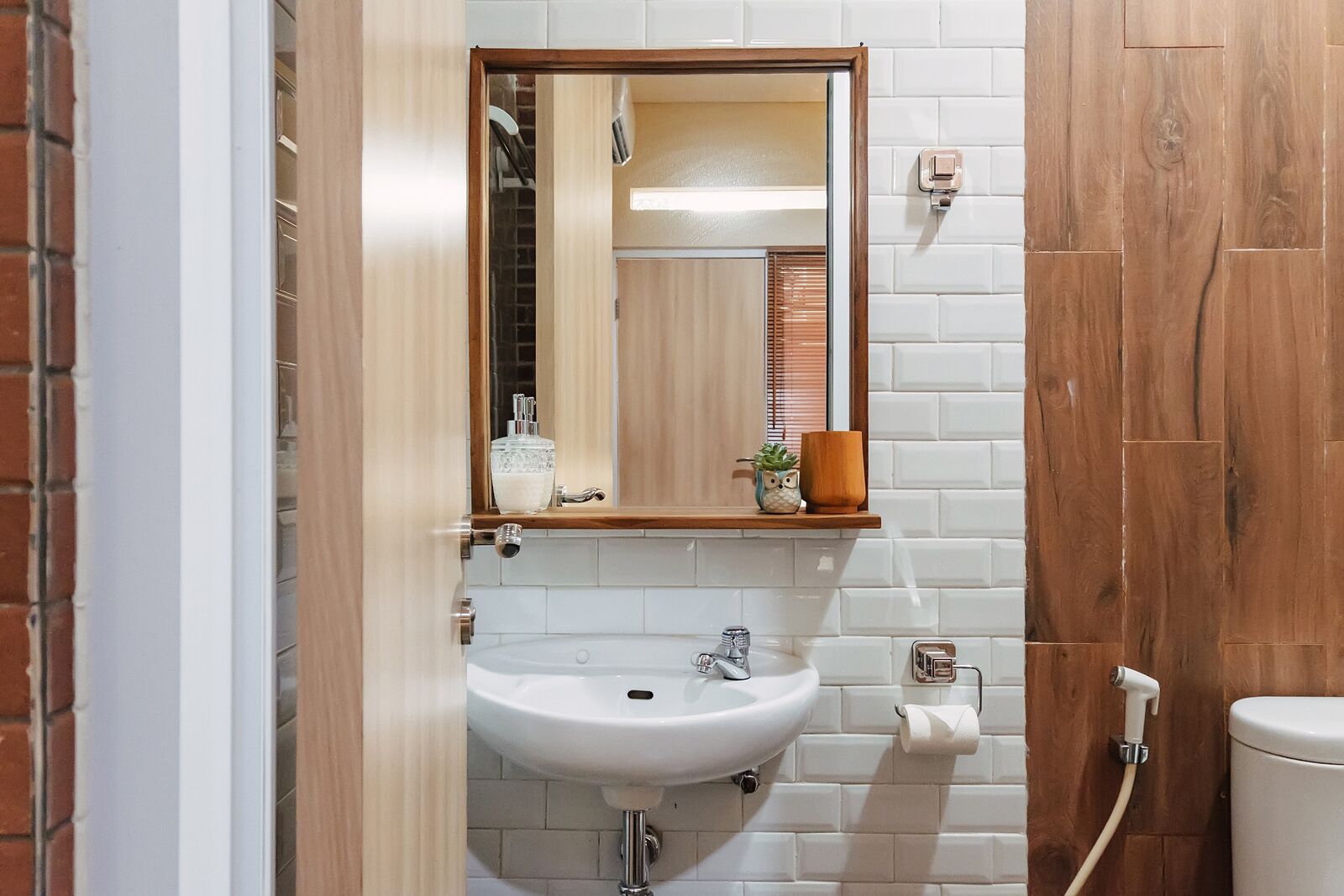 Un baño con lavamanos blanco, tocador de madera y espejo.