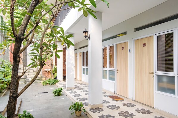 A covered outdoor area with tiled flooring, potted plants, and a tree. - Calma Coliving at Bintaro, Tangerang Selatan (South Tangerang)