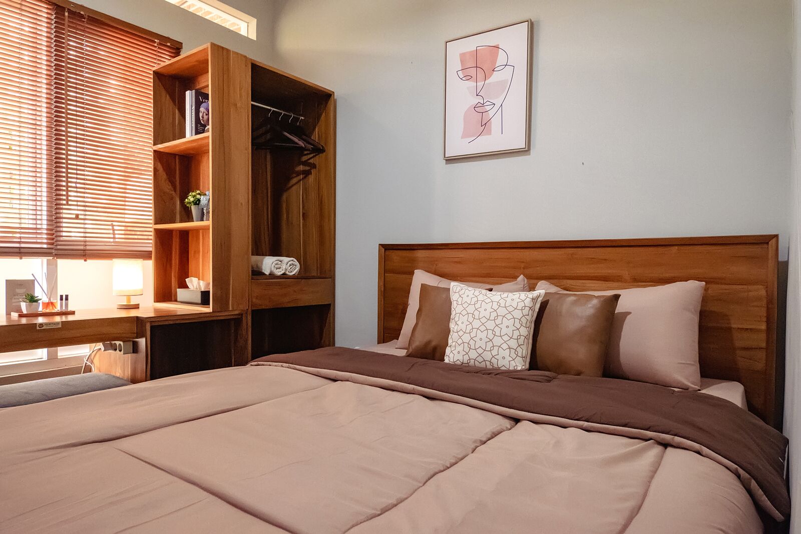 Une chambre à coucher avec un grand lit, une tête de lit en bois et une armoire intégrée dotée d’étagères et d’une tringle pour suspendre les vêtements.