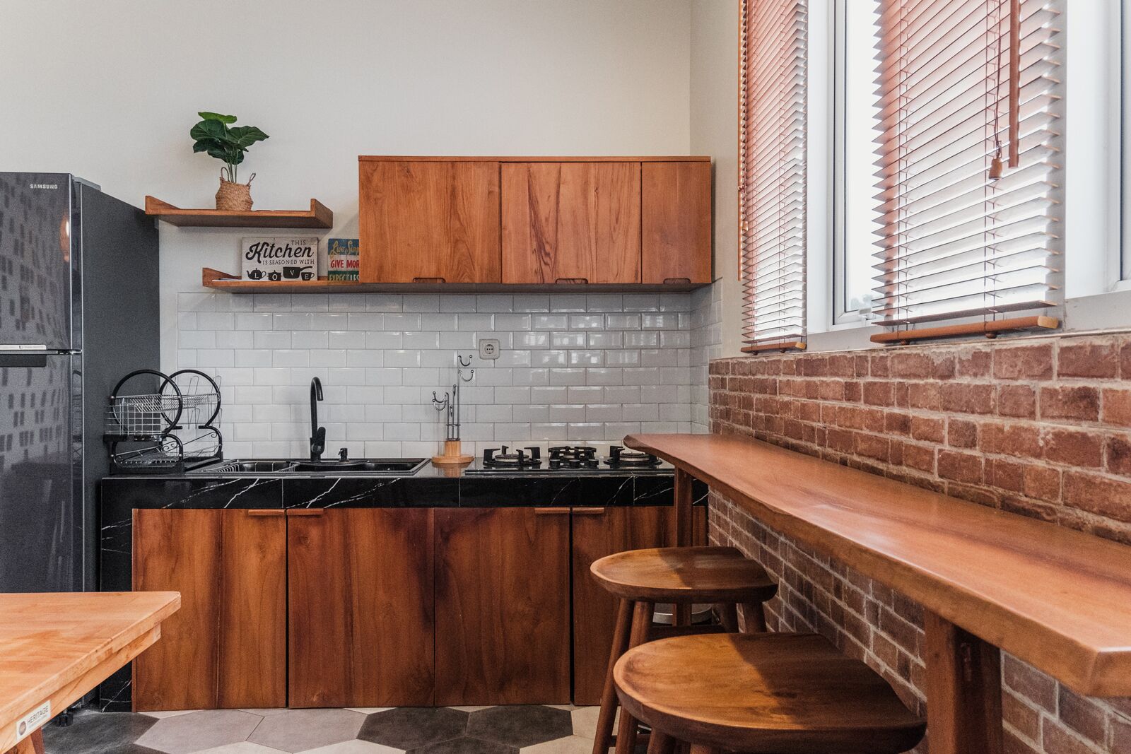 A compact kitchen with wooden cabinets, a black countertop, and a brick accent wall.