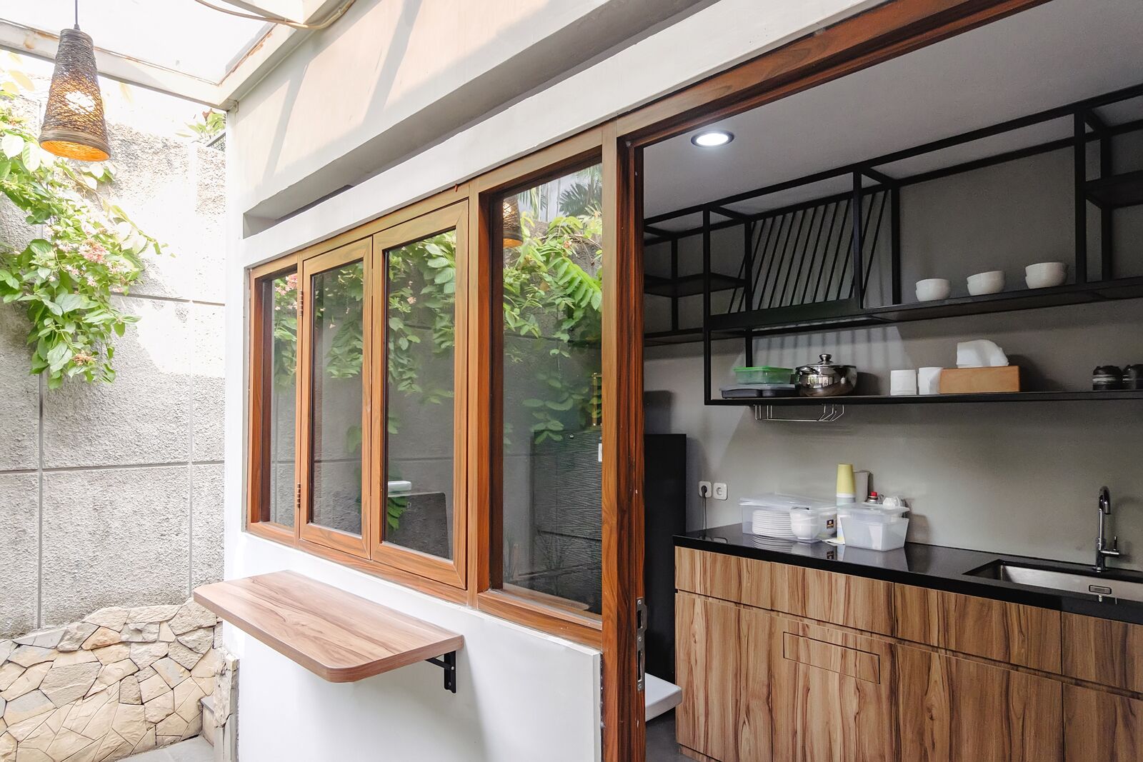 Una cucina moderna con piano di lavoro in legno, lavello e ripiano integrato con stoviglie.