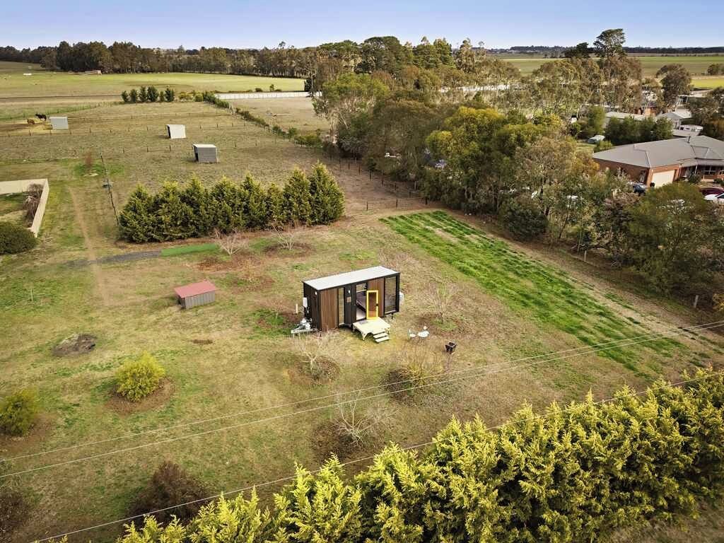 A rural property with a small cabin, open fields, and scattered trees.