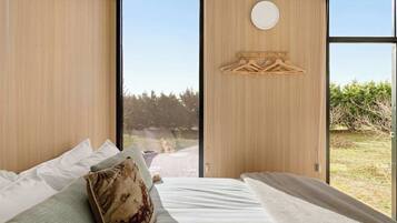 A modern bedroom with a large window, a wooden wall panel, and a circular light fixture.