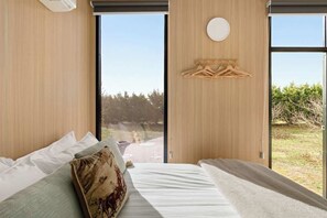 Een moderne slaapkamer met een groot raam, een houten wandpaneel en een ronde lamp.