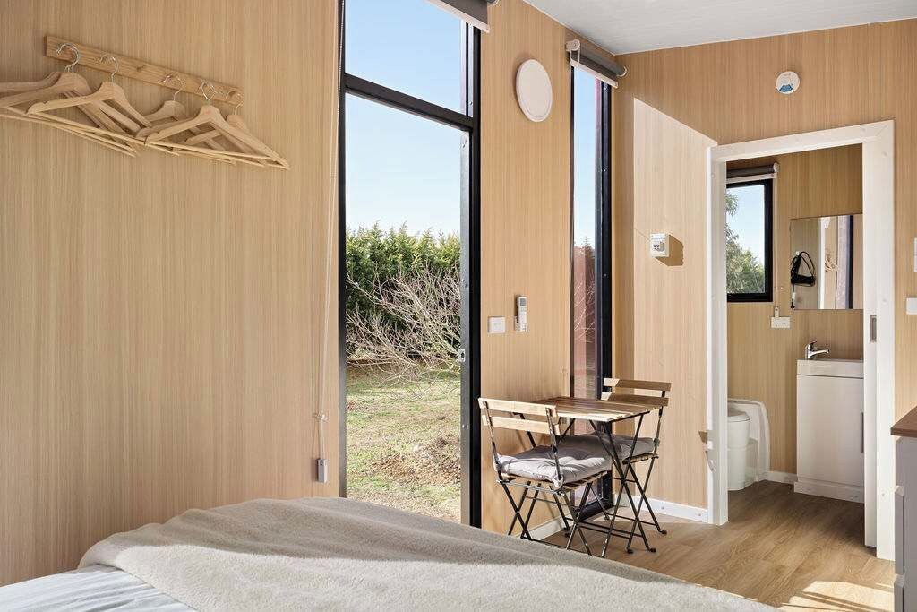 Une chambre moderne avec une grande fenêtre, des meubles en bois et une vue sur l’extérieur.
