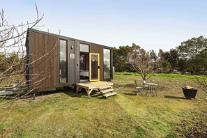 Una casa móvil moderna y compacta con una terraza de madera y un pequeño espacio de estar al aire libre.