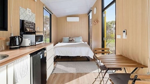 Ein kleines Schlafzimmer mit Bett, Nachttisch und Blick ins Freie.
