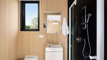 A modern bathroom with a wooden wall, a window, a sink, a toilet, and a shower.