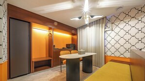Quarto de hotel com escrivaninha de madeira, sofá, mesa e ventoinha no teto.