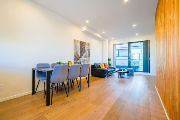 A modern living space with a dining area, sofa, and a large window.