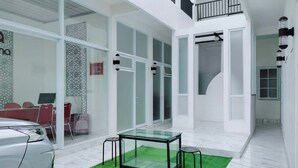 A modern interior with a glass table, red chairs, and a white car. - TwoSpaces at Arfina Residence Syariah, Lamongan (Paciran)