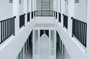A modern building with a central atrium, white walls, and black railings. - TwoSpaces at Arfina Residence Syariah, Lamongan (Paciran)