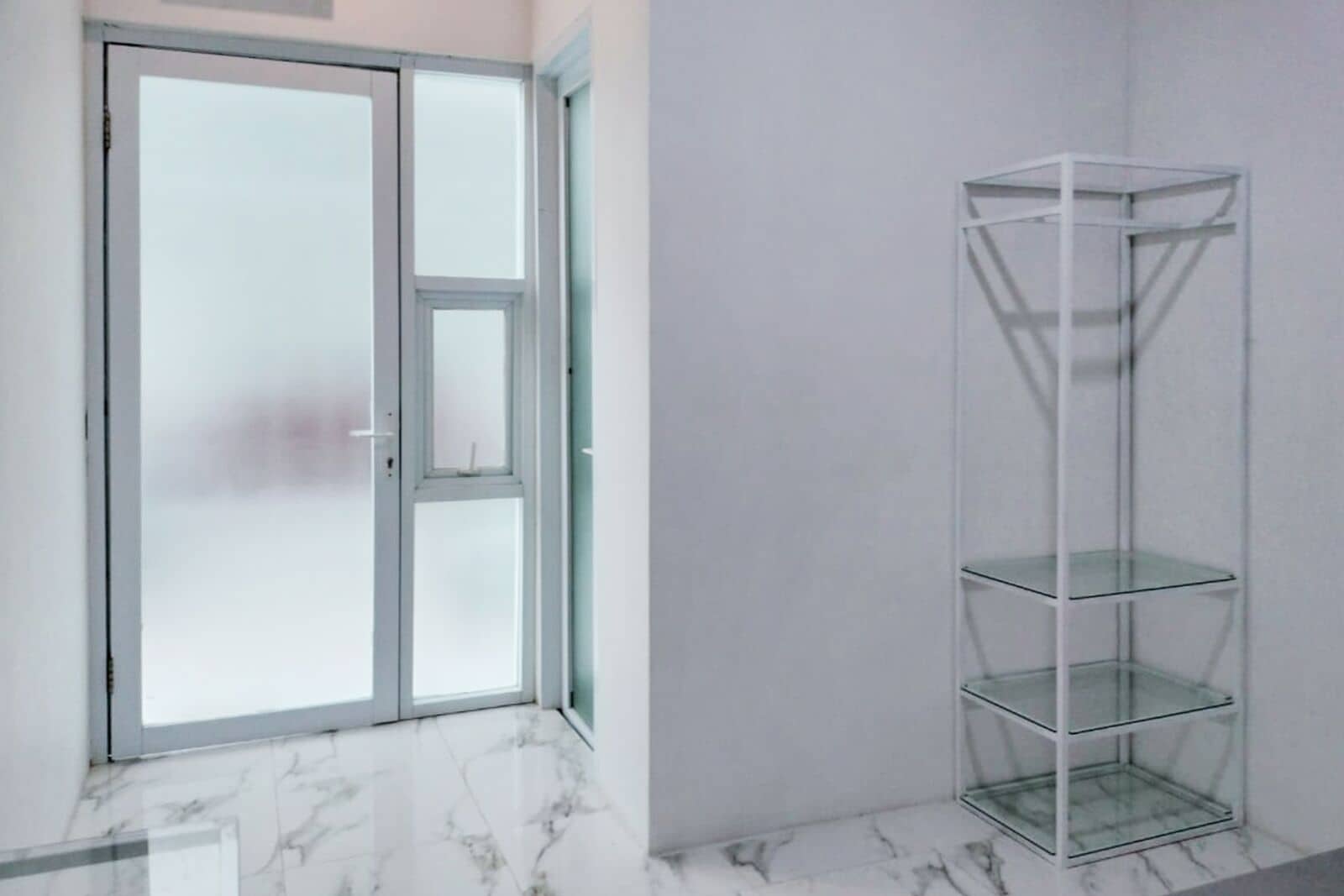 A room with a frosted glass door, a marble floor, and a white shelving unit.