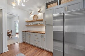 A kitchen with light gray cabinets, a stainless steel refrigerator, and wooden countertops. - The Stranger Stay - Blocks from Film Site (Rome)